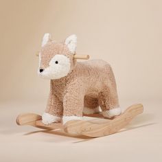 a small stuffed animal on a wooden rocking horse with white fur and black nose, sitting in front of a beige background