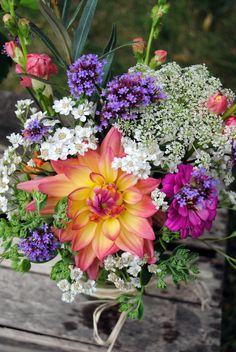 a bouquet of flowers sitting on top of a wooden bench