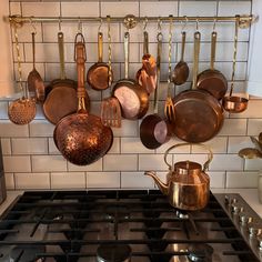 pots and pans are hanging on the wall above the stove