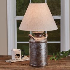 a table lamp sitting on top of a wooden table next to a cup and saucer