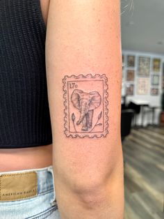 an elephant stamp tattoo on the left arm