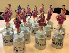 a group of cheerleader figurines sitting on top of silver canisters