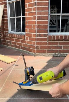 a person using a power drill to cut plywood planks on the ground with a pair of scissors