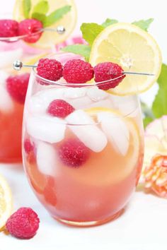 raspberry lemonade punch in a glass with ice and garnishes