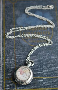 "Silver World Map Pocket Watch Necklace Made with a glass antique map cabochon and silver pocket watch. Carry the world with you! This traveler necklace is created with a real, working pocket watch that measures 1.5x2\" and hangs from a 32\" extra long chain. The pendant is adorned with a high quality antique map print that has been sealed behind a 25mm magnifying glass dome. All jewelry comes packaged in a kraft cotton filled box with an elastic ribbon ready to gift! Note: These necklaces are w Pocket Necklace, Globe Necklace, Gift For Traveler, Map Jewelry, Travel Necklace, Pocket Watch Necklace, Silver Pocket Watch, Elastic Ribbon, Map Necklace