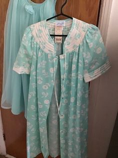 New old stock, robe housecoat with Marshall's tag, Size Small.  This in a floral turquoise and white quilted polyester cotton blend,  with a pocket on the right side. Short sleeves.  Stud closures all the way down the front, small ribbons to tie a bow at the neck.  Length: 40 inches Shoulder to shoulder: 32 inches Bust about 34 inches. Waist 34 inches Arm opening 14 inches. Free shipping on all nightwear, will combine shipping. Heidi Gibson, Girls Camp, Nightgowns For Women, Womens Robes, 1980s Vintage, Nightwear, Night Gown, Made In Usa, Lounge Wear