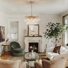 a living room filled with furniture and a fire place under a chandelier in front of a fireplace