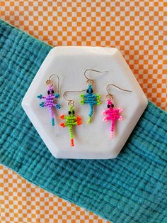 three small colorful earrings on top of a white plate