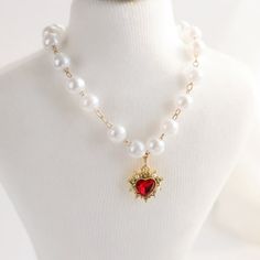 a white mannequin with a red heart and pearl necklace on it's neck