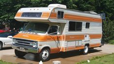 an orange and white camper parked next to other cars