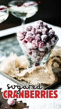 a glass bowl filled with cranberries sitting on top of a table next to two glasses