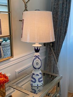 a blue and white lamp sitting on top of a glass table next to a mirror