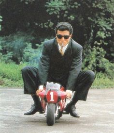 a man in suit and sunglasses riding a motorcycle