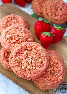 strawberry shortbread cookies on a cutting board with strawberries in the background