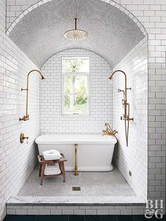 a bathroom with white tile and gold fixtures