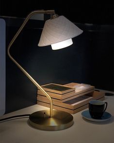 a desk lamp sitting on top of a table next to a cup and saucer