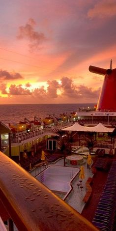 the sun is setting over an outdoor swimming pool and deck area on a cruise ship