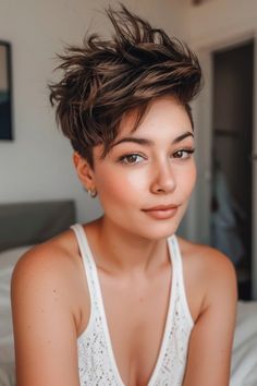 Person with short, tousled hair and hoop earring, posing confidently in a sleeveless top.