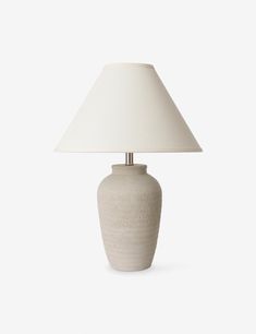 a white table lamp with a beige shade on the base and a light bulb attached to it