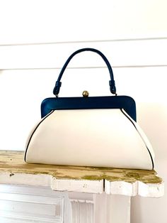 "Vintage vinyl spectator handbag. Extra large size. Little wear( photos show marks), clean interior, no Oder, strong clasp and handle.  The lean of the bag is an intentional design; not mis-shapen. The back is meant to lay flatter against the body. Pretty smart actually.  Measurements are approximate  Height 8\" not including clasp  Width 14\" Depth 4\" Strap drop 6\"" Vintage Bag Design, White Retro Satchel With Detachable Strap, Retro Blue Bags For Formal Occasions, Retro Blue Evening Bags, Blue Retro Evening Bag, Vintage Blue Bag With Detachable Strap, Retro Blue Top Handle Shoulder Bag, Vintage Blue Top Handle Satchel, Blue Vintage Satchel With Detachable Strap