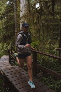 a woman running across a wooden bridge in the woods