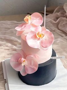 there is a pink cake with flowers on the top and one candle in the middle