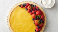 a pie topped with berries and blueberries on top of a white marble countertop