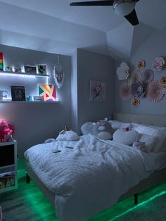 a white bed sitting in a bedroom next to a green light under a ceiling fan