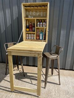 an outdoor bar with two chairs and a table in front of it, next to a metal wall