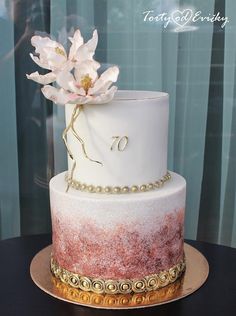 a white and red cake with flowers on top sitting on a gold plated platter