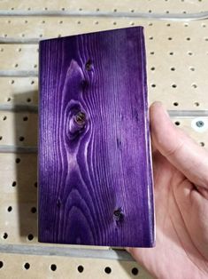 a hand holding a purple piece of wood