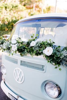 an old vw bus decorated with flowers and greenery