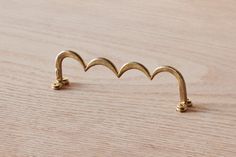 a pair of gold ear clips sitting on top of a wooden table