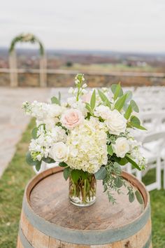 a vase filled with white flowers sitting on top of a wooden barrel