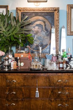 an old dresser with many items on it and a large painting above the top shelf