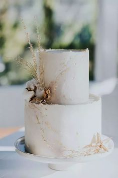 a three tiered wedding cake with dried flowers on top