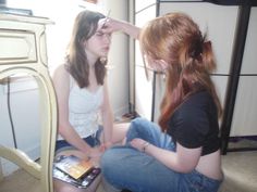 two young women sitting on the floor looking at their cell phones in front of them