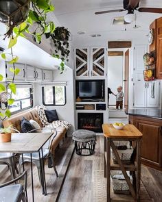 a living room and dining area in a recreational vehicle with wood flooring, white walls and ceiling fan