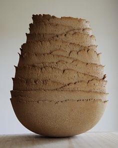 a brown vase sitting on top of a wooden table next to a white wall in the background