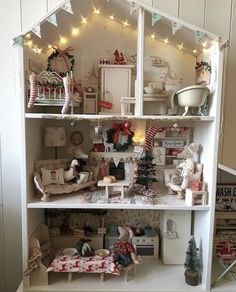 a doll house with lots of furniture and christmas decorations on the top shelf in front of it