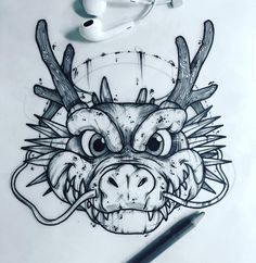 a drawing of a dragon's head with horns and eyes drawn on white paper