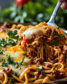 a fork full of spaghetti with meat and cheese