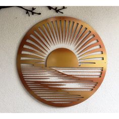 a circular metal wall hanging with a sun design on the side and birds flying in the background