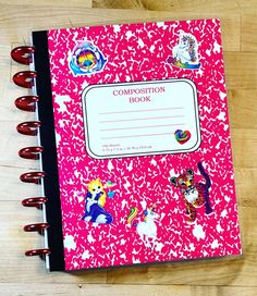 a pink composition book with stickers on it