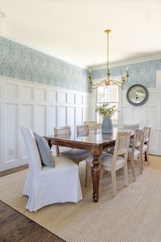 a dining room table and chairs with a clock on the wall