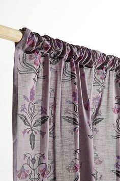 the curtain is open and has purple flowers on it, along with a wooden rod