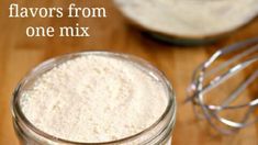 a glass jar filled with flour next to a whisk on a wooden table