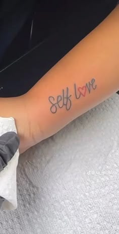 a woman's arm with the word self love tattooed on her left arm, in black ink