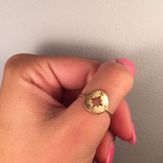 a woman's hand holding a gold ring with a star on the middle and an oval design