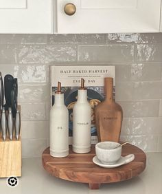 kitchen utensils and cookbook on counter with white tile backsplash in background